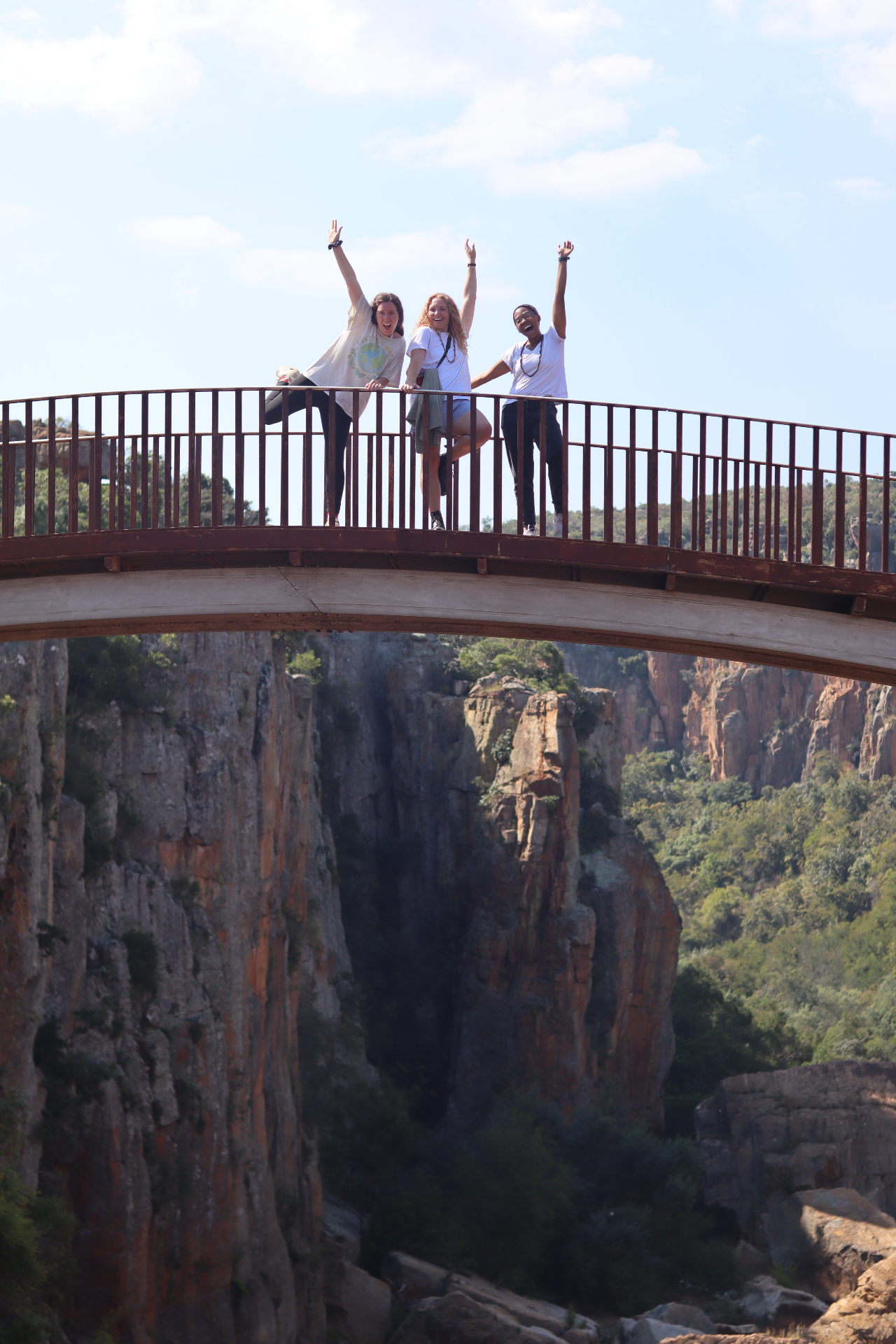 Three squad members cheering on a bridge above Blyde River Canyon