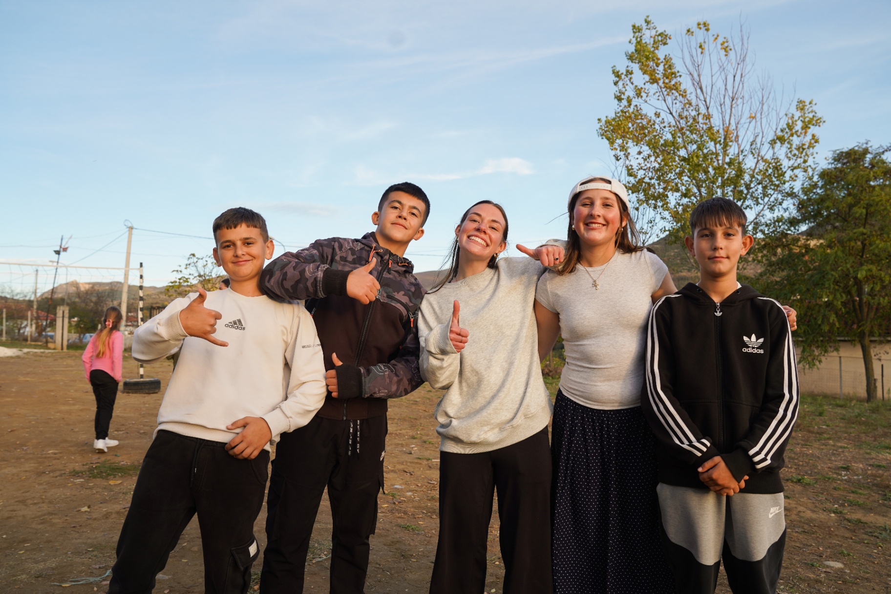 Squad member with four Albanian teens posing together at sunset
