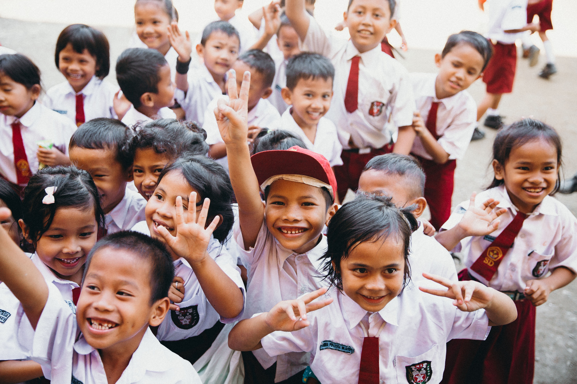 Indonesian schoolchildren in uniforms smiling and waving