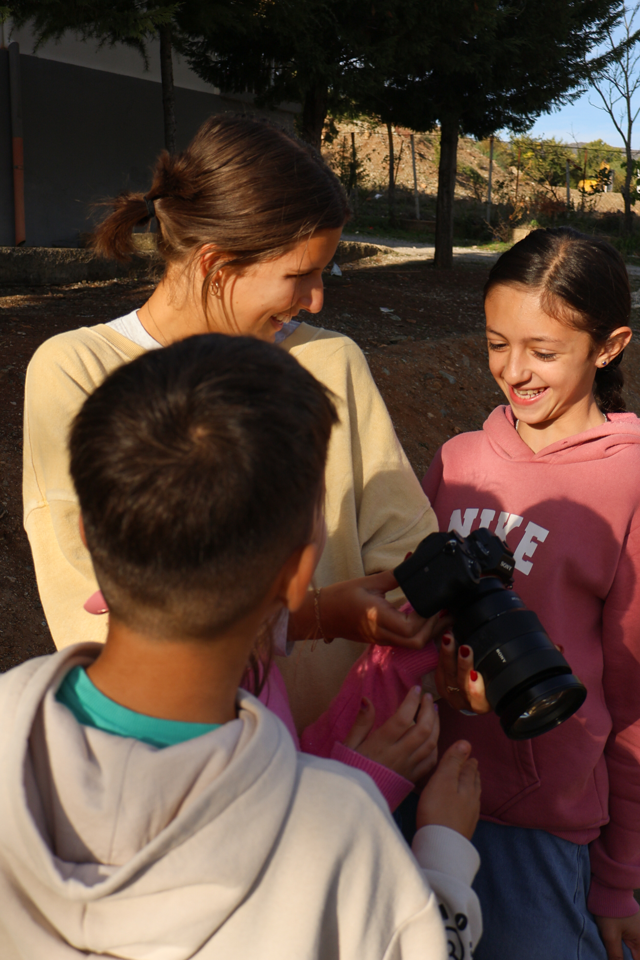 Squad member showing photos on a camera screen to two Albanian kids