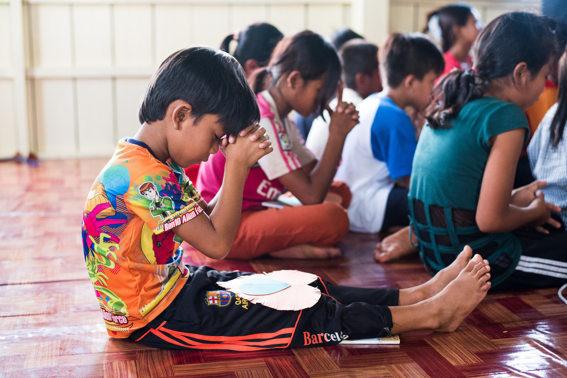 Young boy praying during ministry gathering in Cambodia