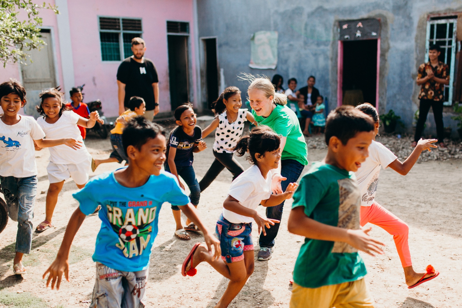 Squad member running and laughing with village kids in Indonesia