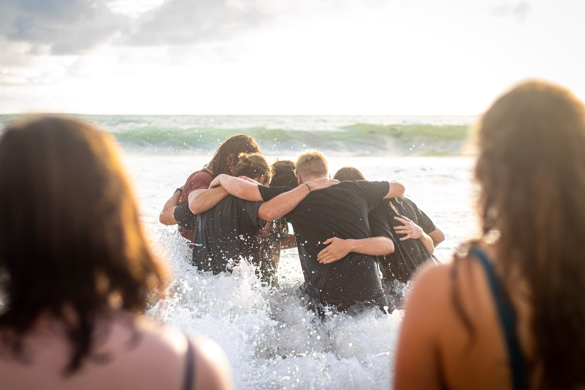 Students linked arm in arm in the ocean at sunset in Costa Rica
