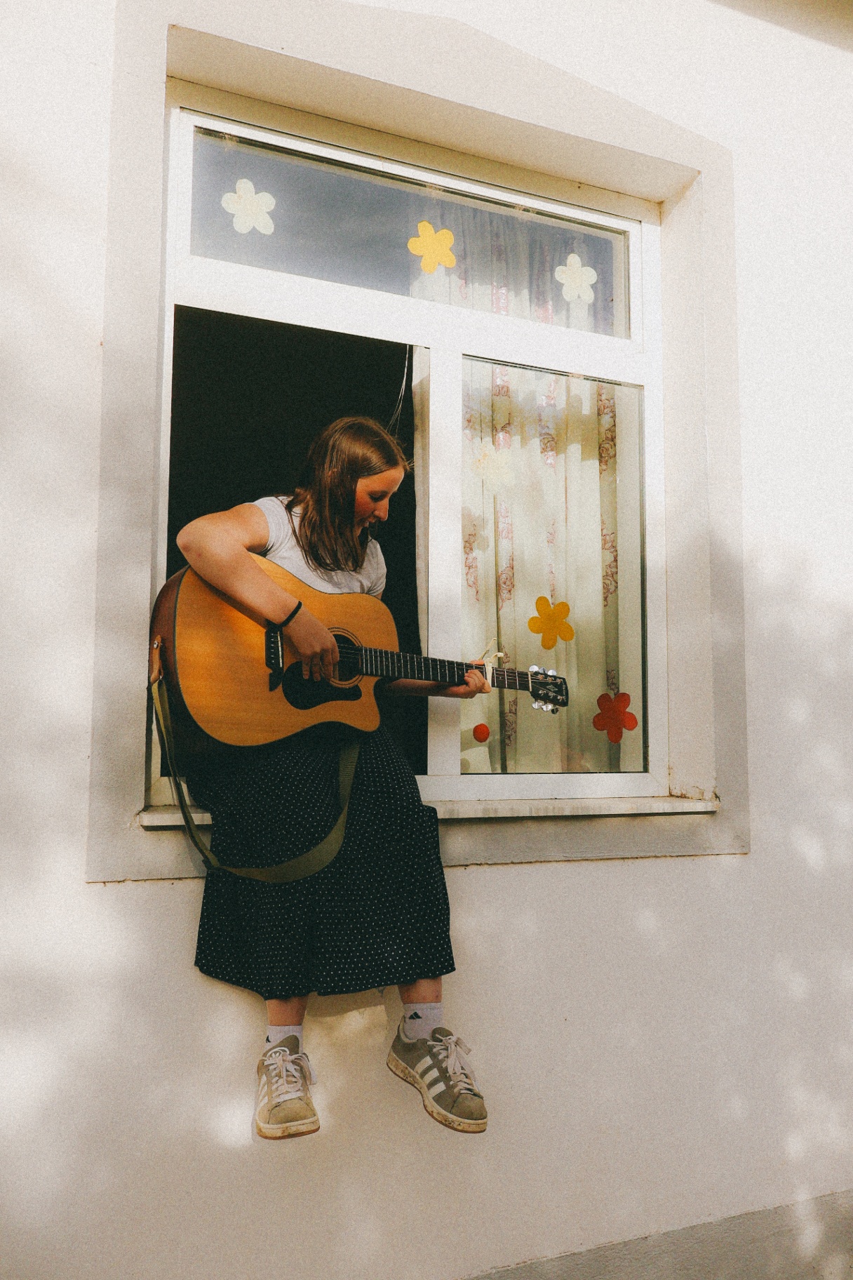 Squad member playing acoustic guitar on a windowsill in Albania