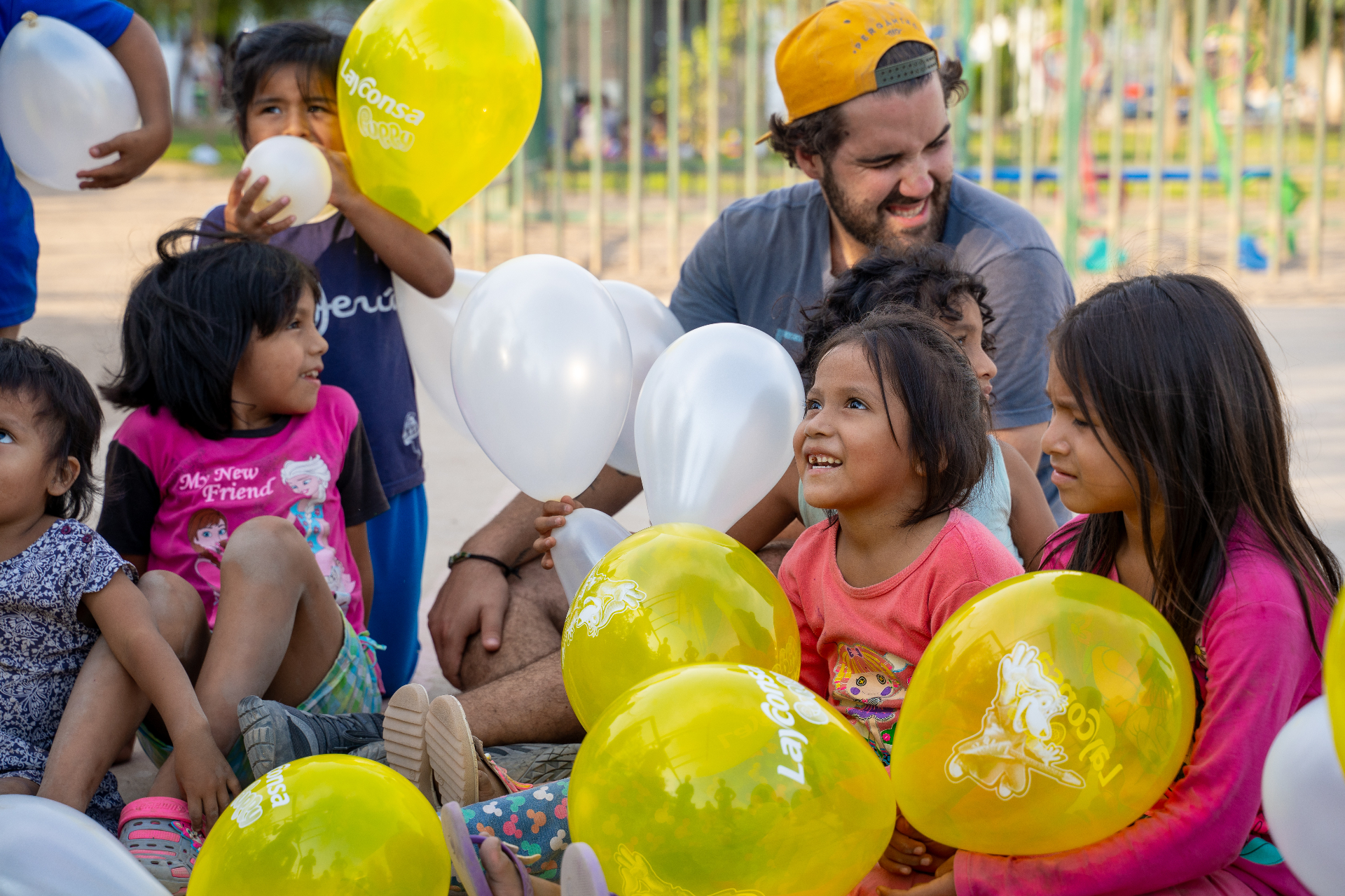 Squad member sitting with Peruvian children holding balloons