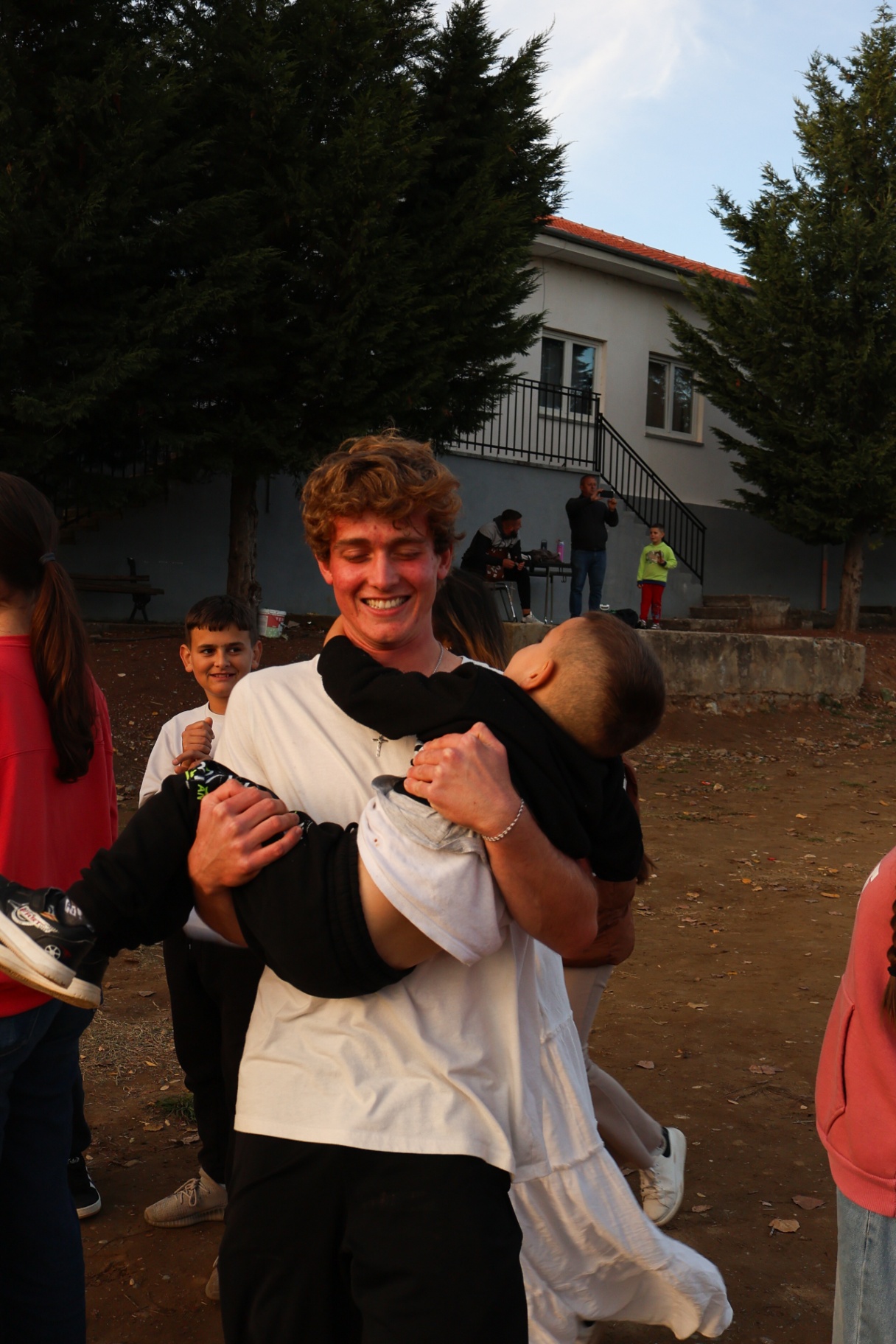 Squad member laughing while carrying a young boy in his arms in Albania