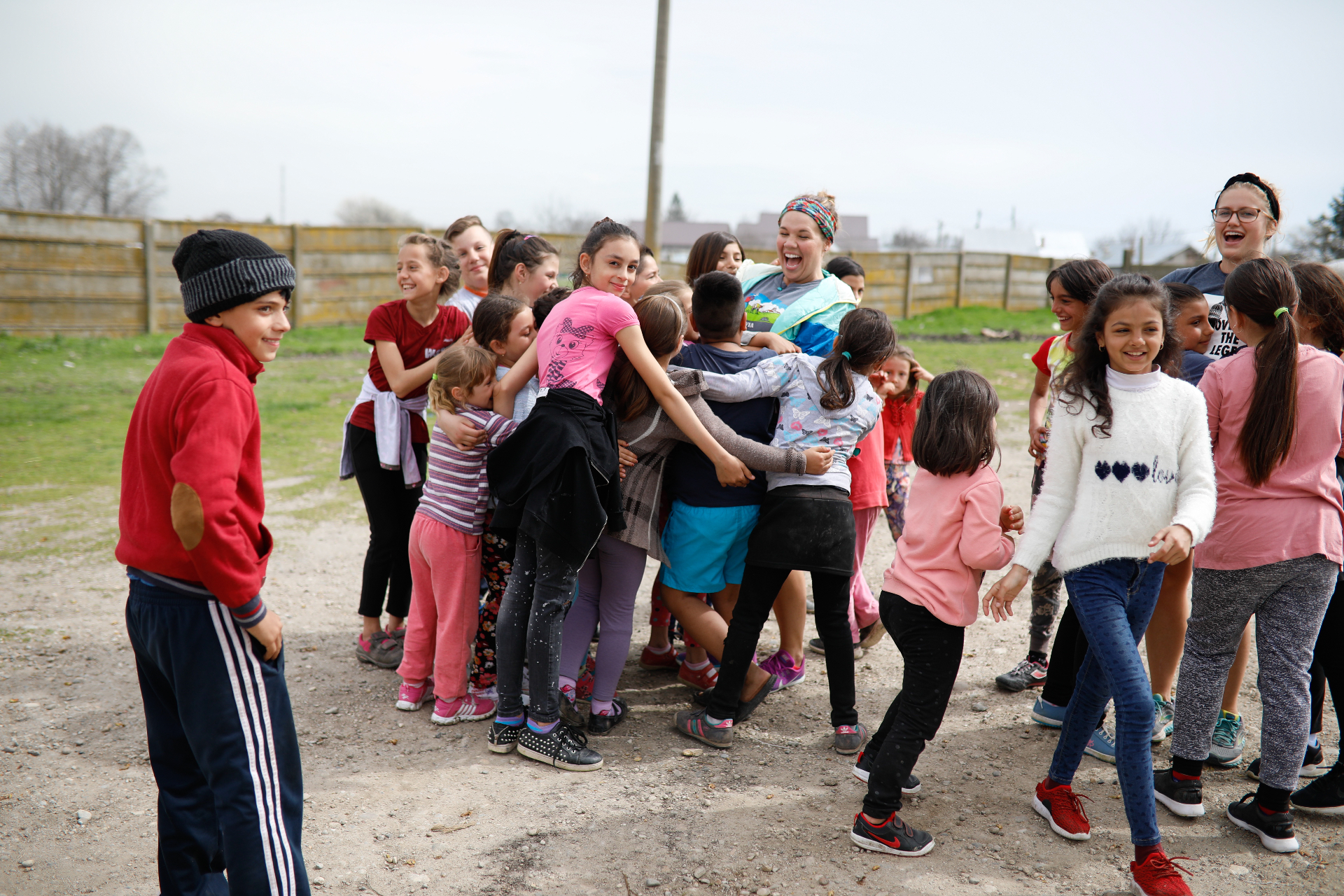 Squad member surrounded by Romanian kids in a giant group hug