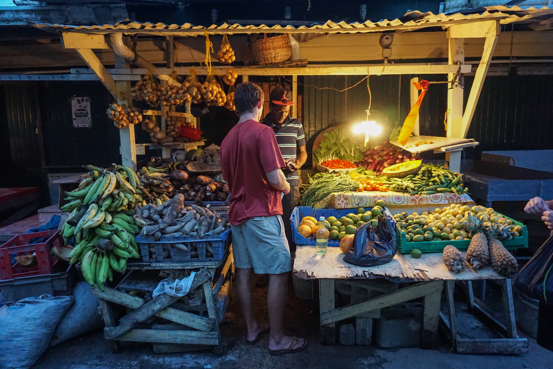 Squad member buying produce at a Brazilian market stall at night