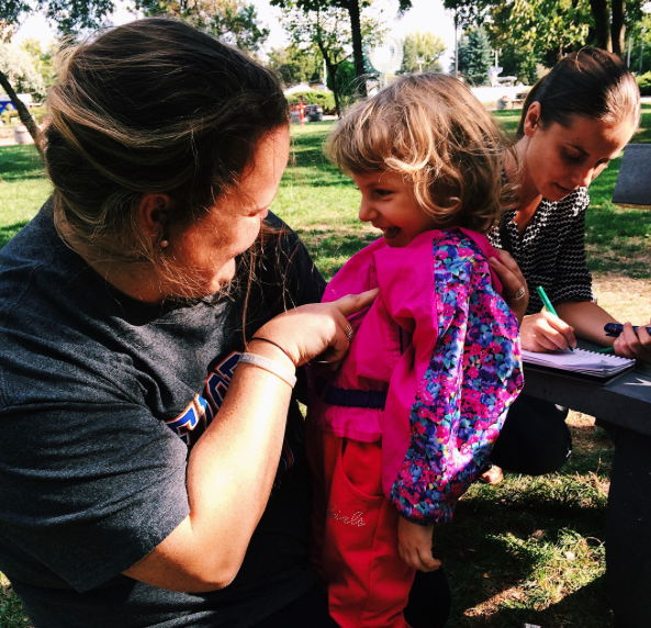 Squad member helping a young Romanian girl into a vest